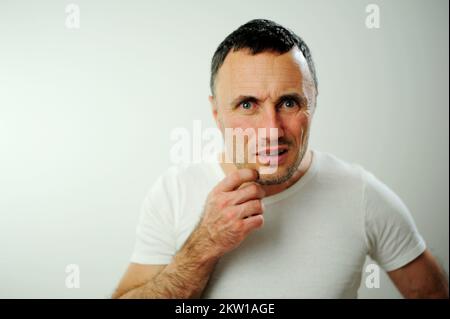 Zeigen Sie mit dem Finger direkt auf die Kamera wütender, unrasierter Mann sieht in den Rahmen, sind Sie ernsthaft verwirrt Unzufriedenheit Enttäuschung Negative Emotionen Weißes Studio Stockfoto