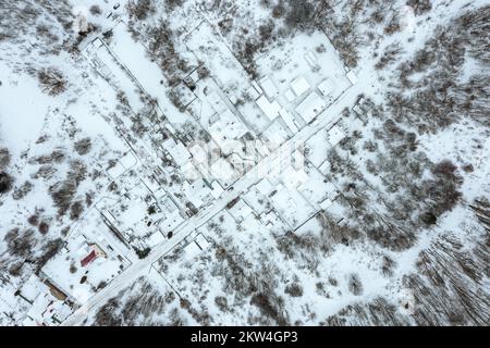 Kleines Dorf mit schneebedeckten Häusern und Straße. Winterlandschaft. Draufsicht. Stockfoto