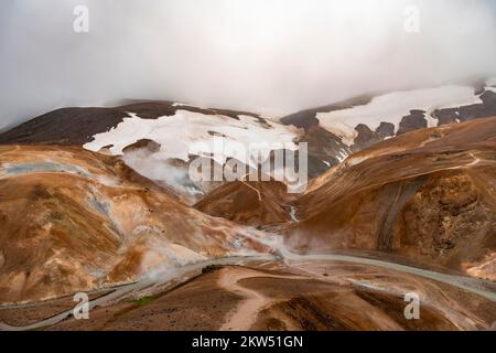 Brücke und dampfende Bäche zwischen farbenfrohen Rhyolitenbergen und Schneefeldern, geothermisches Gebiet Hveradalir, Kerlingarfjöll, isländische Highlands, Icel Stockfoto