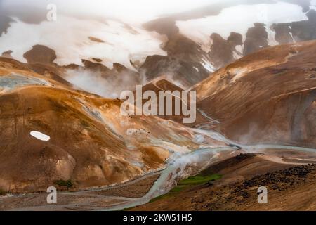 Brücke und dampfende Bäche zwischen farbenfrohen Rhyolitenbergen und Schneefeldern, geothermisches Gebiet Hveradalir, Kerlingarfjöll, isländische Highlands, Icel Stockfoto