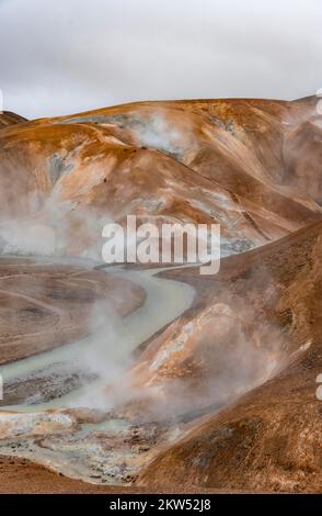 Brücke und dampfende Bäche zwischen farbenfrohen Rhyolitenbergen und Schneefeldern, geothermisches Gebiet Hveradalir, Kerlingarfjöll, isländische Highlands, Icel Stockfoto