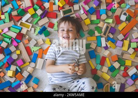 Holzziegel aus Montessori-Material, Regenbogenspektrum. Der kleine süße Junge spielt mit Würfeln. Stockfoto