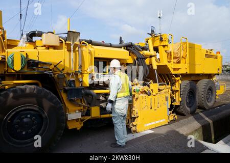 Die Kaltfräsmaschine entfernt den alten Asphalt. Instandsetzung der Fahrbahnoberfläche. Straßenarbeiten. Stockfoto