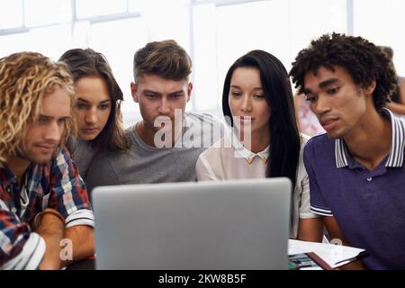 Das ist interessant. Eine Gruppe junger Studenten, die an einem Laptop zusammenarbeiten. Stockfoto