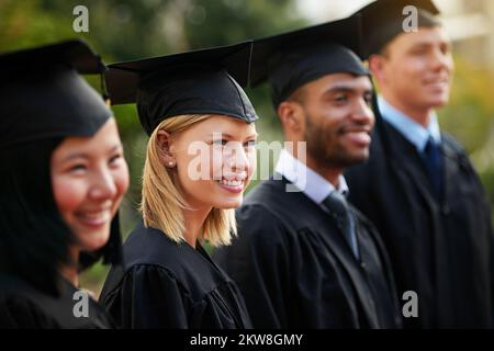 Es ist an der Zeit, deine Träume zu starten. Eine Gruppe junger Hochschulabsolventen, die in einer Reihe stehen. Stockfoto