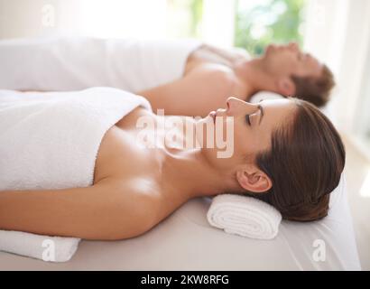 Genießen Sie einen Tag der Verwöhnung. Ein Mann und eine Frau liegen zusammen auf Massageliegen. Stockfoto