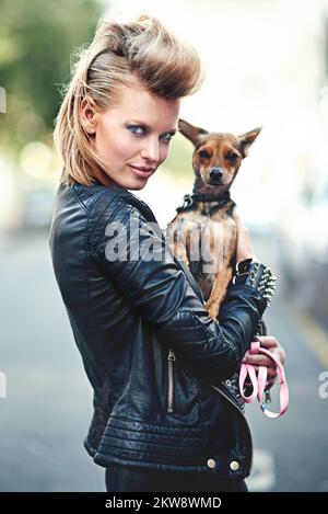 Er ist mein kleiner Rockstar. Verkürztes Porträt einer gerissenen jungen Frau, die ihren kleinen Hund draußen hält. Stockfoto