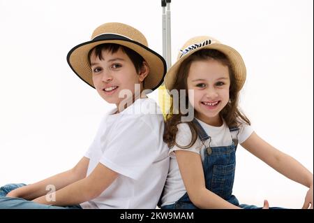 Reizende Kinder, Bruder und Schwester, die im Sommer Urlaub machen, ins Ausland reisen, ein Lächeln vor der Kamera, isolierter weißer Hintergrund Stockfoto