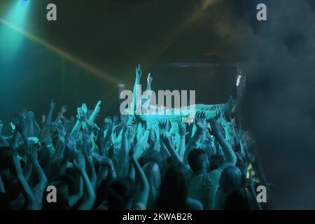 Surfen in der Menge. Ein Bühnentaucher, der auf einem Rockkonzert durch das Publikum getragen wird. Stockfoto