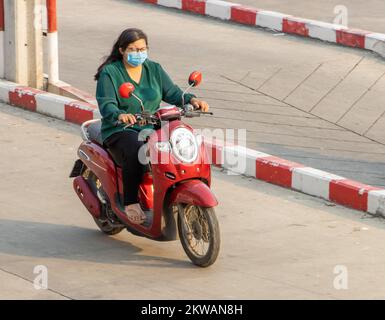 SAMUT PRAKAN, THAILAND, MÄRZ 02 2022, Eine Frau mit Gesichtsmaske fährt ein Motorrad Stockfoto