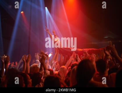 Surfen in einer Menge von Fans. Ein Bühnentaucher, der auf einem Rockkonzert durch das Publikum getragen wird. Stockfoto