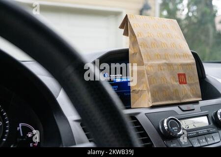 McDonalds Fast-Food-Tasche auf dem Armaturenbrett eines Lieferwagens, der vor einer Garage geparkt ist. (USA) Stockfoto