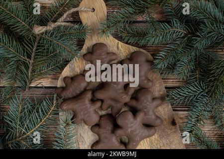 Schokoladen-Lebkuchen-Männerkekse und Weihnachtsbaumzweige. Weihnachten Weihnachten Winter flach liegend Komposition. Stockfoto