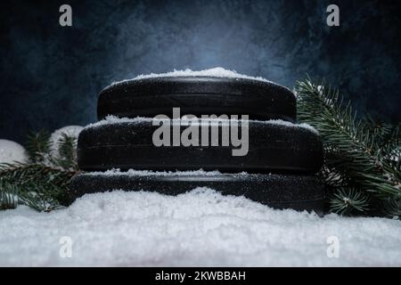 Gym-Kurzhanteln-Gewichtsteller, Weihnachtsbaumzweige auf Schnee. Fitness-Feiertage Winterzusammensetzung. Workout-Konzept, Training bei kaltem Wetter. Stockfoto