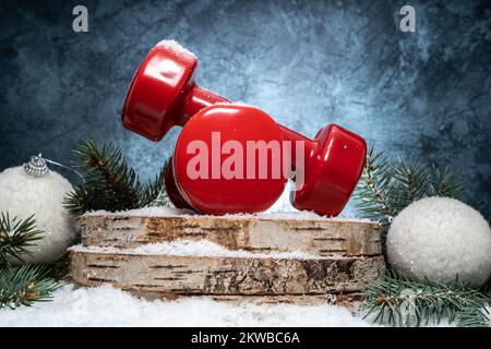 Hanteln auf Holzscheiben, Weihnachtsbäume auf Schnee. Zusammensetzung der Fitness-Feiertage. Winter-Workout-Konzept, Training bei kaltem Wetter. Stockfoto