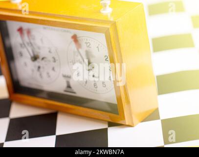 Die klassische mechanische Schachuhr auf einem Holzschachbrett. Selektiver Fokus Stockfoto