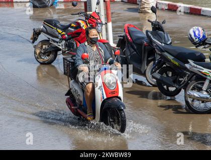 SAMUT PRAKAN, THAILAND, Okt 29 2022, Eine Frau fährt Motorrad auf einer überfluteten Straße Stockfoto