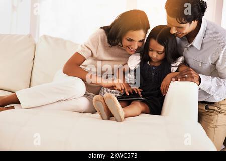 Zeig uns, was du tust... ein Bild einer liebevollen jungen Familie, die sich ein digitales Tablet teilt. Stockfoto