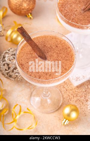 Eierpunsch-Martini-Cocktail mit Zimt und Muskatnuss, goldene Weihnachtsdekorationen und Bokeh-Effekt, Kopierbereich Stockfoto