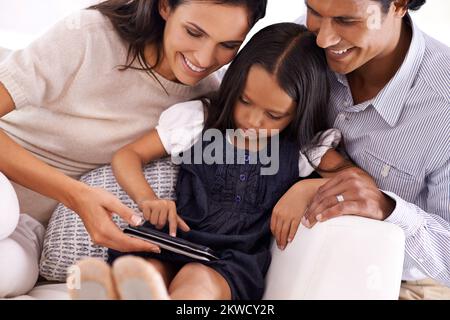 Sie zeigen ihnen, wie es gemacht wird. Eine liebevolle junge Familie, die sich ein digitales Tablet teilt. Stockfoto