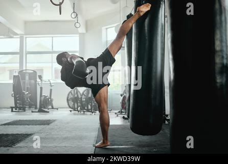 Professionelles, fittes und aktives männliches Kampftraining mit einem Boxsack im Fitnessstudio. Kickboxer-Training, Training und Fitness-Training für Wettkämpfe Stockfoto