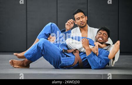 Männer kämpfen im Karate-Wettkampf, trainieren Schüler im Fitness-Kurs und lernen Kampfkunst im Sportverein zusammen. Starke Trainer-Leistung Stockfoto