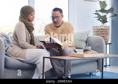 Verehren, moslem und Paar, die den koran für Dankbarkeit lesen, auf dem Sofa in ihrem Wohnzimmer zusammen. Islam, Ruhestand und Seniorenmann und -Frau mit einem Stockfoto