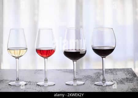 Gläser mit verschiedenen Weinsorten, rot, weiß, rosa und bordeaux auf weißem Hintergrund. Wunderschöner abstrakter Weinhintergrund Stockfoto