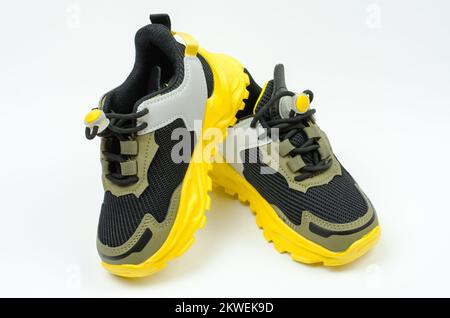 Kinder-Sport-Sneaker mit gelber Sohle auf weißem Hintergrund. Khaki Sneaker. Sportschuhe. Stockfoto