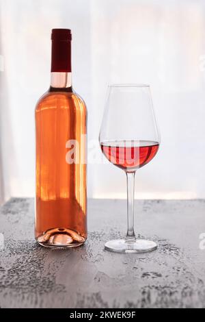 Weinflasche mit Rosenweinglas auf schwarzem Hintergrund. Luxuriöses Konzept für Weinproben. Stockfoto