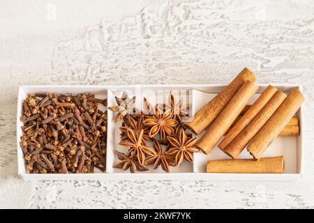 Verschiedene Gewürze, Zimt, Nelken, Sternanis auf weißem Hintergrund. Traditioneller Weihnachtsgeruch und Backzutaten im Hintergrund. Stockfoto
