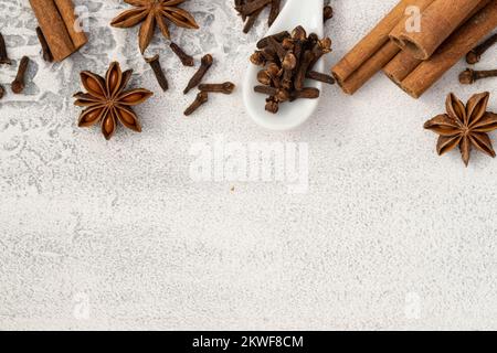 Verschiedene Gewürze, Zimt, Nelken, Sternanis auf weißem Hintergrund. Traditioneller Weihnachtsgeruch und Backzutaten im Hintergrund. Stockfoto