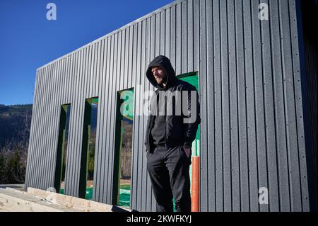 Männlicher Ingenieur, der ein Holzrahmenhaus baut Mann steht auf der Baustelle und überprüft die Qualität der Arbeit. Stockfoto