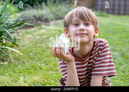 Der Junge hält das Modell des Hauses in seinen Händen. Stockfoto