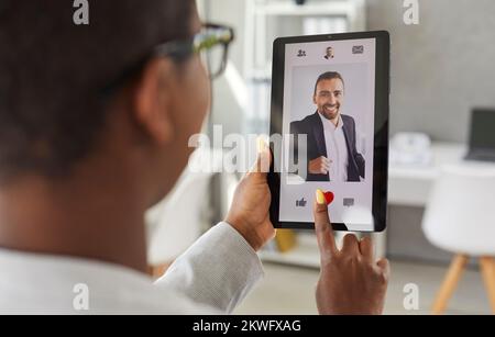 Frau verwendet Tablet und gibt in einer Online-Dating-App oder -Website ein Foto von einem Mann Stockfoto