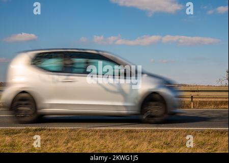 Kleine Autos fahren über die Landstraße vor blauem Himmel Stockfoto