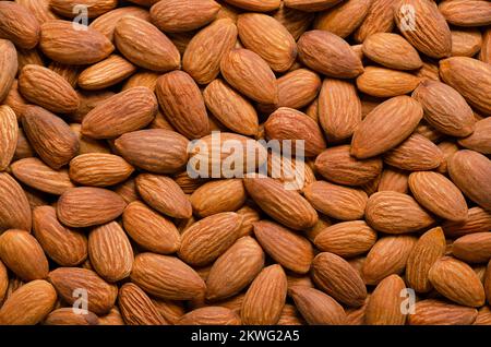 Geschälte Mandeln, Hintergrund von oben. Rohe, genießbare und getrocknete Nüsse, botanische Tropfen, Samen und Früchte von Prunus dulcis. Stockfoto