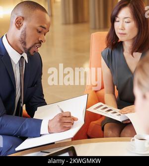 Terminplaner-, Finanz- und Geschäftsleute in einer Besprechung planen und eine Finanzagenda in einem Notizbuch verfassen. Vielfalt, Zusammenarbeit und schwarzer Mann Stockfoto