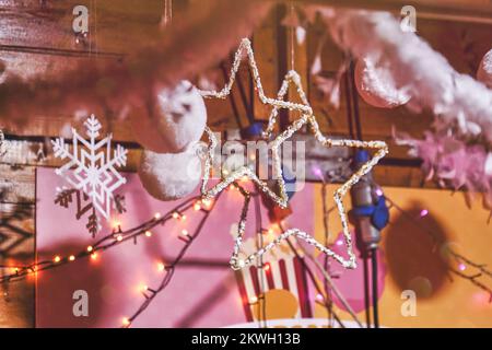 Pinkfarbene flauschige Weihnachtsbälle und Gerlandbälle dekorieren das Teenagerzimmer zu Weihnachten. Stockfoto