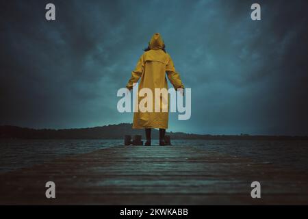 Person mit gelbem Mantel und dramatischer Wolkenlandschaft Stockfoto