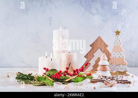 Weihnachtsdekoration mit Kerzen und hölzernen Weihnachtsbäumen Stockfoto