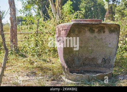 Ein großer traditioneller beschädigter Wasserbehälter auf einer Farm im ländlichen Thailand. Stockfoto