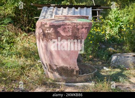 Ein großer traditioneller beschädigter Wasserbehälter auf einer Farm im ländlichen Thailand. Stockfoto