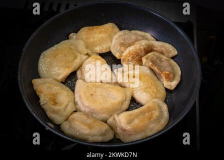 Gebratene Knödel mit Kohl, Käse und Kartoffeln in einem Topf mit Schmalz. Die Haut ist braun und braun. Stockfoto