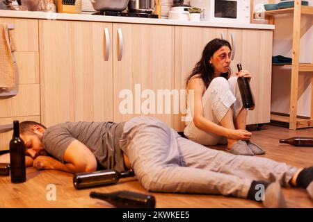 Missbraucht Frau Alkohol trinken in der Nähe betrunken und abussive Mann in der Küche. Alkoholiker aggressiver Mann missbraucht Verletzungen erschrocken, Angst, geschlagen und in Panik versetzt Frau. Stockfoto