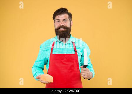 Bereit zum Essen. Das Käsekonzept. Käsehersteller, eigene Firma. Hipster mit Bart in Küchenschürze. Molkerei-Lebensmittelgeschäft. Käsefest. Diät und Stockfoto