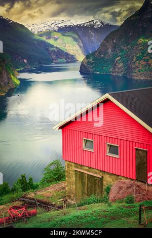 Norwegischer Rorbu über dem Aurlandsfjord mit Reflexion und Boot, Norwegen, Nordisch Stockfoto