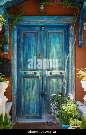 Wunderschöne blaue Tür eines Straßencafés, dekoriert mit Dekor und Blumen mit Pflanzen. Hochwertiges Foto Stockfoto