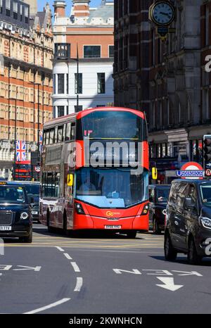 Roter Doppeldeckerbus im Verkehr auf einer Straße in Knightsbridge, London. Stockfoto