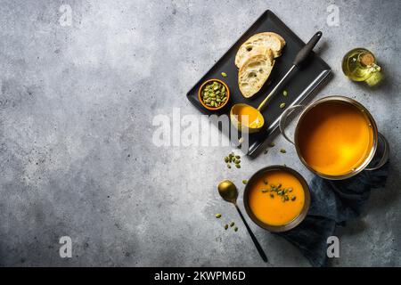 Kürbissuppe im Topf am Steintisch. Stockfoto